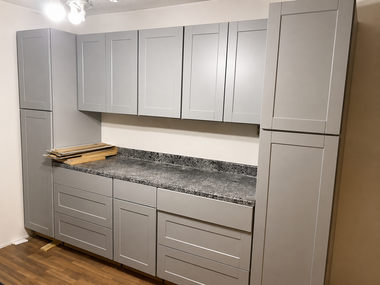 Gray kitchen cabinets with granite countertop and wood floor, shown in a small room