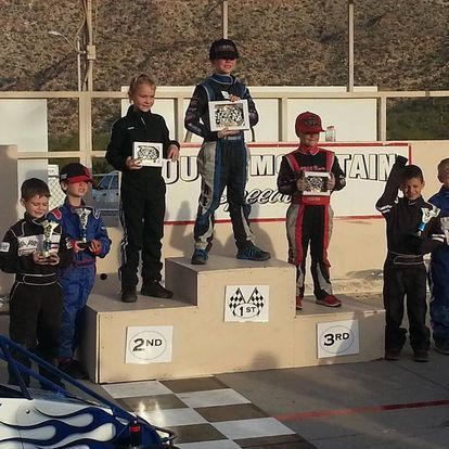 A group of young boys are standing on a podium holding trophies