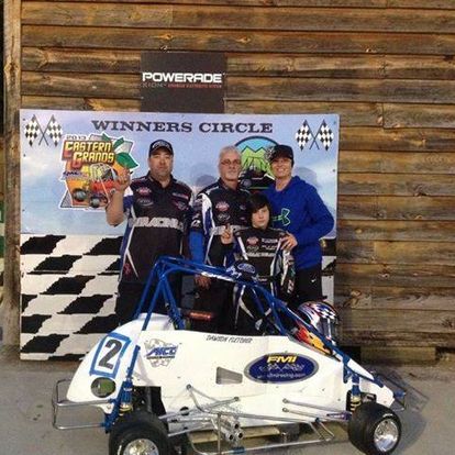 A group of people standing next to a go kart.