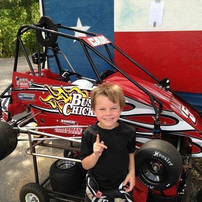 A young boy is standing in front of a buggy that says buck chick