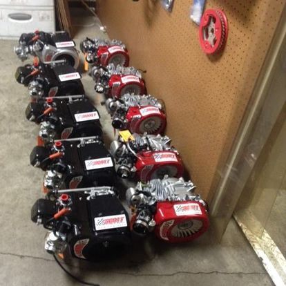 A row of lawn mower engines are lined up in a garage