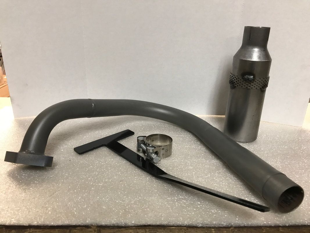 A metal pipe is sitting on a white surface next to a bottle.