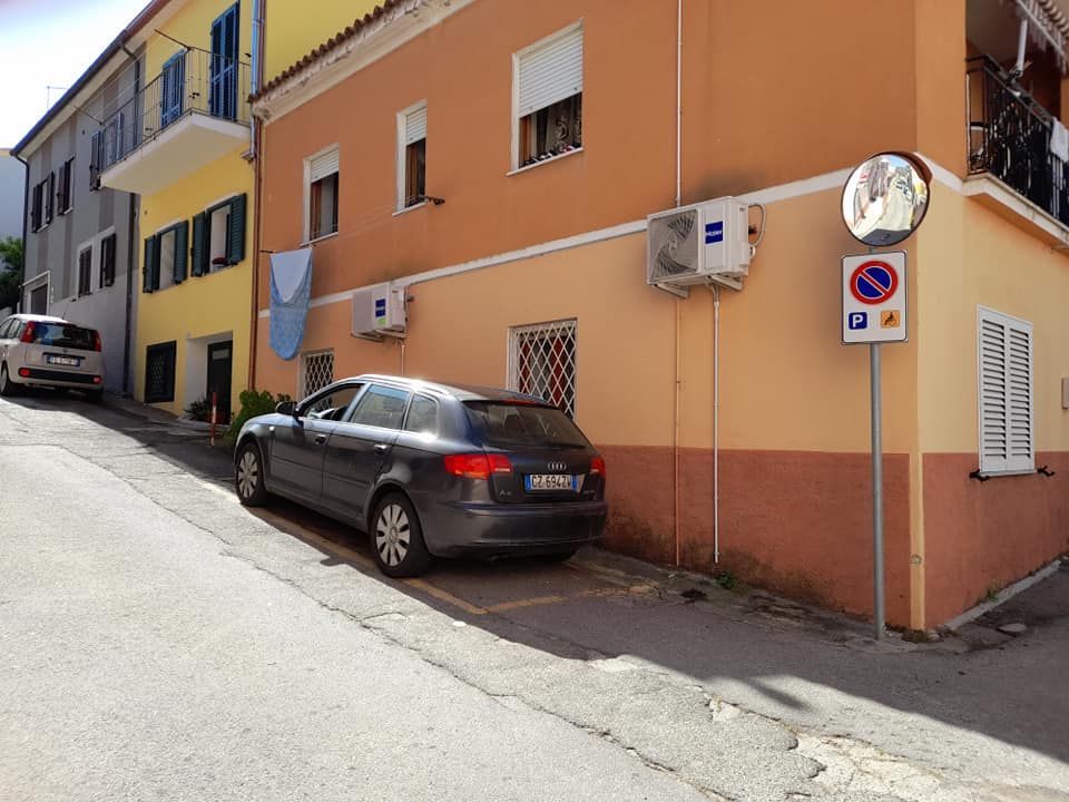 edificio giallo e arancione con un cartello di parcheggio.