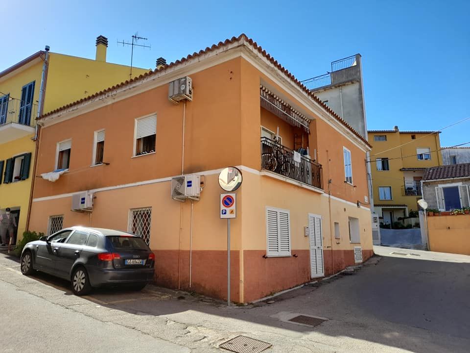 Un edificio arancione e marrone a due piani all'angolo, con un'auto parcheggiata di fronte e un cielo azzurro e limpido.