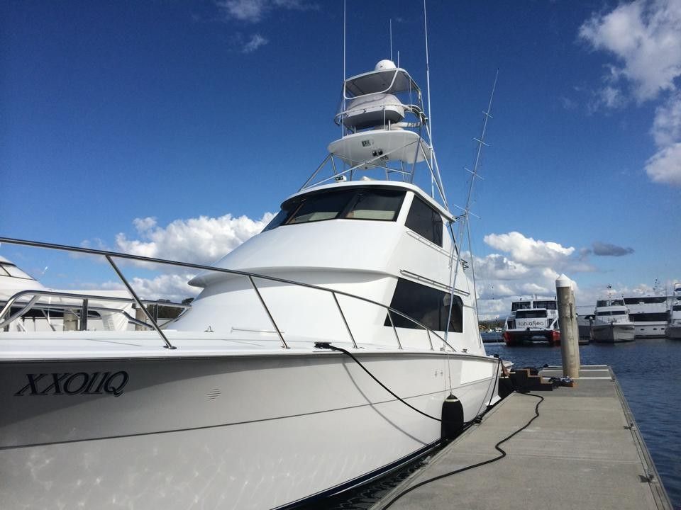 White yacht docked at a pier, under a blue sky with clouds.