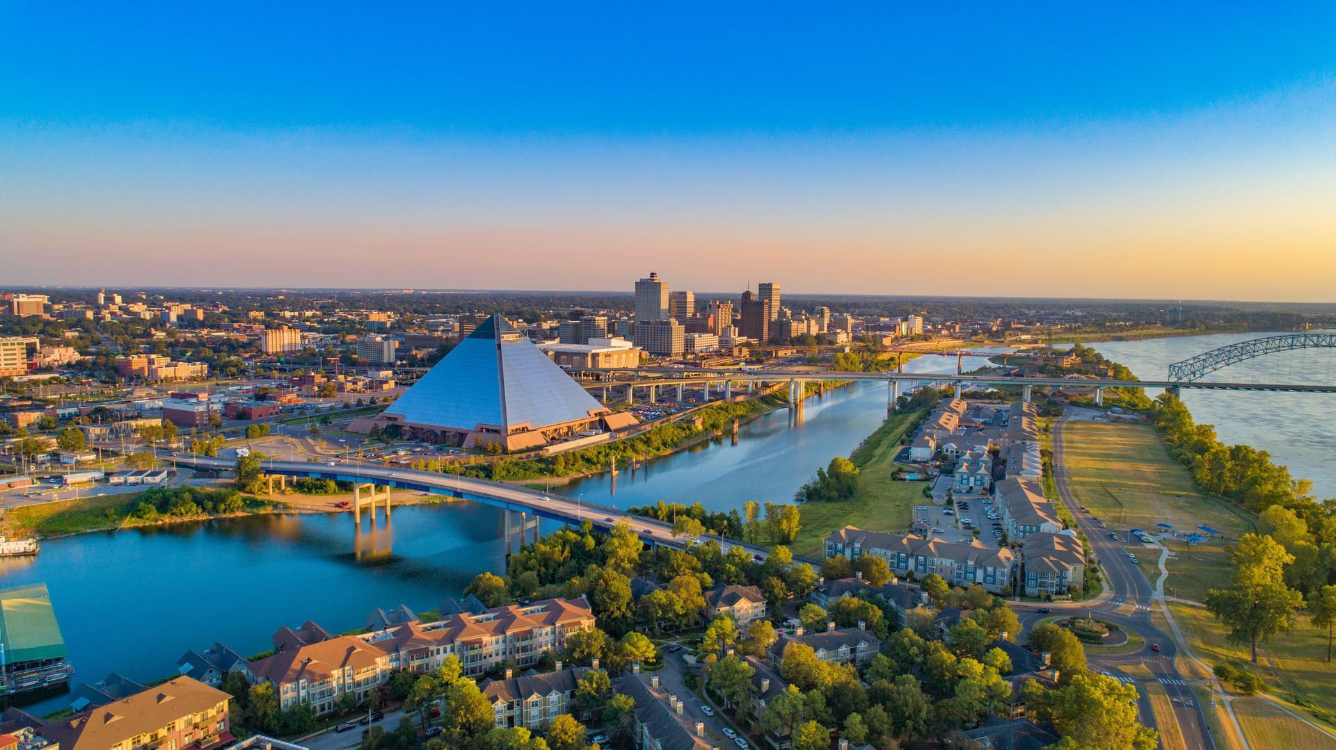 Aerial view of Memphis, TN skyline at sunset; includes the Pyramid Arena, river, and bridges.
