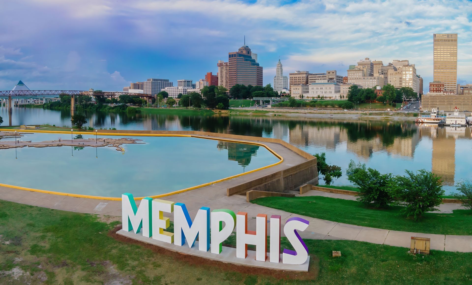 Memphis skyline with the city's name in colorful letters in the foreground; river and bridge in view.