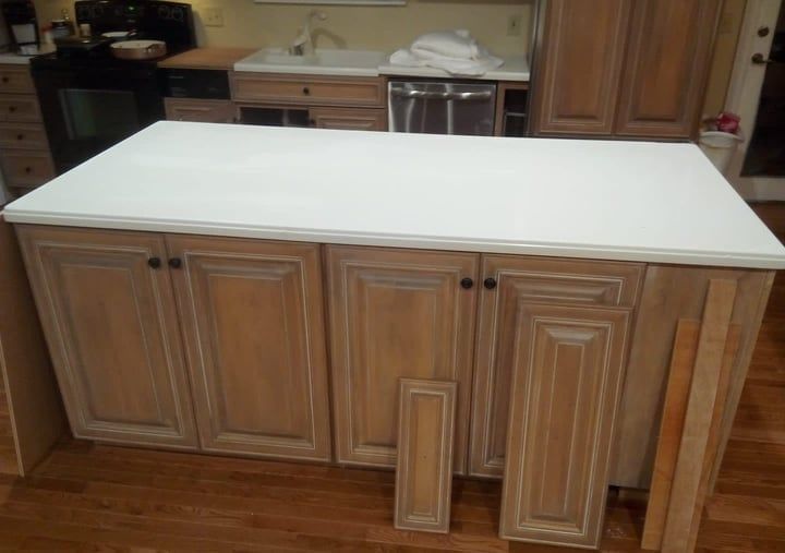 Kitchen island with a white countertop and light brown cabinets.