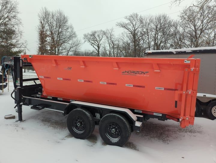 Orange trailer with a bin on a snowy ground.