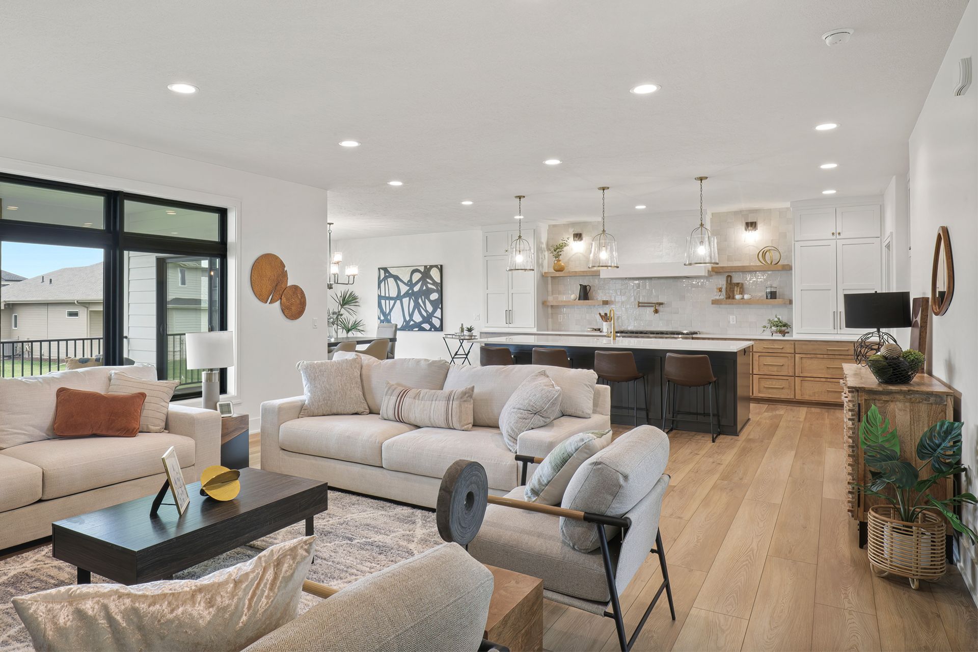 Open-concept living space with white walls, lights, wood floors, and a modern kitchen.