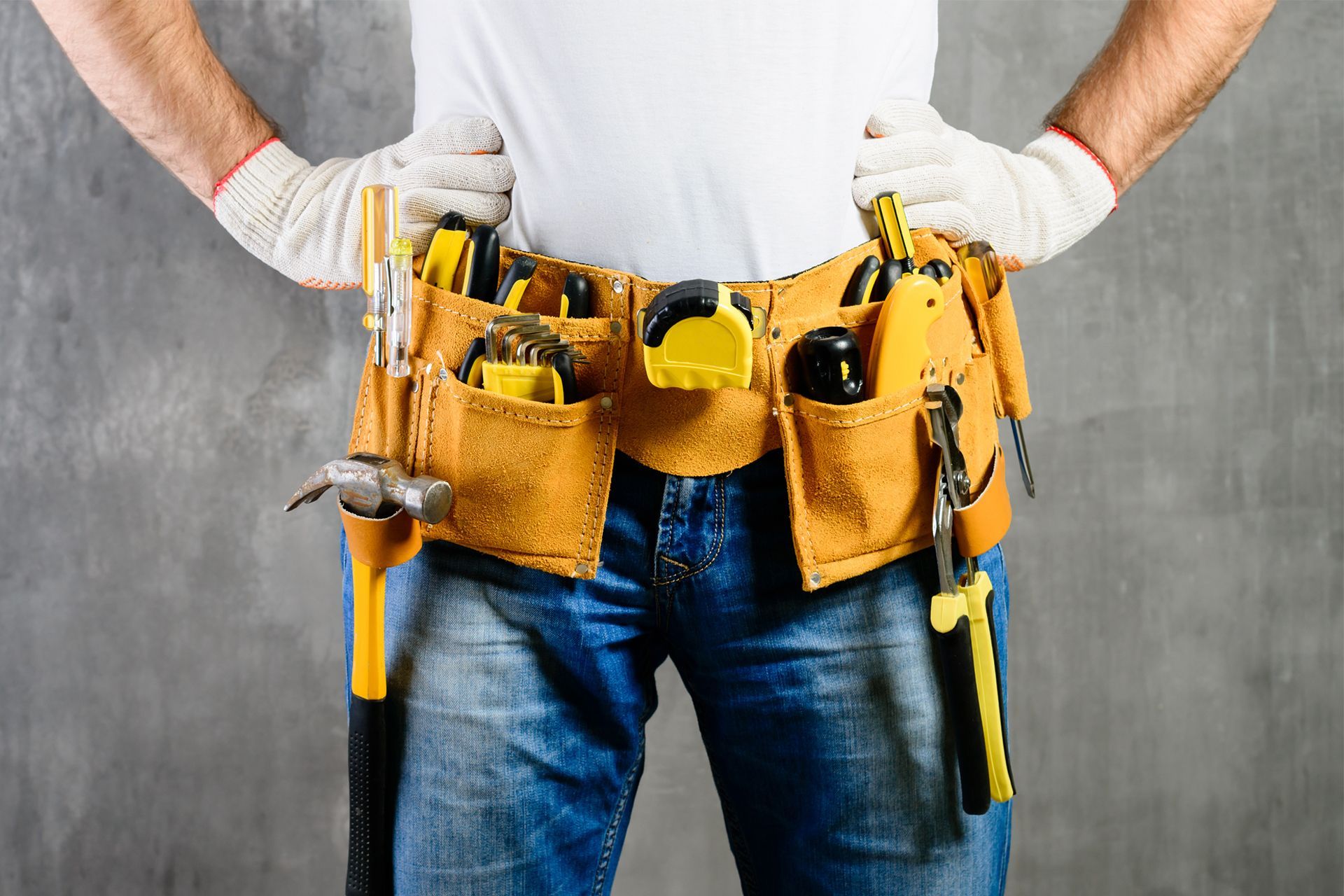 Worker wearing a tool belt, hands on hips, ready to work.