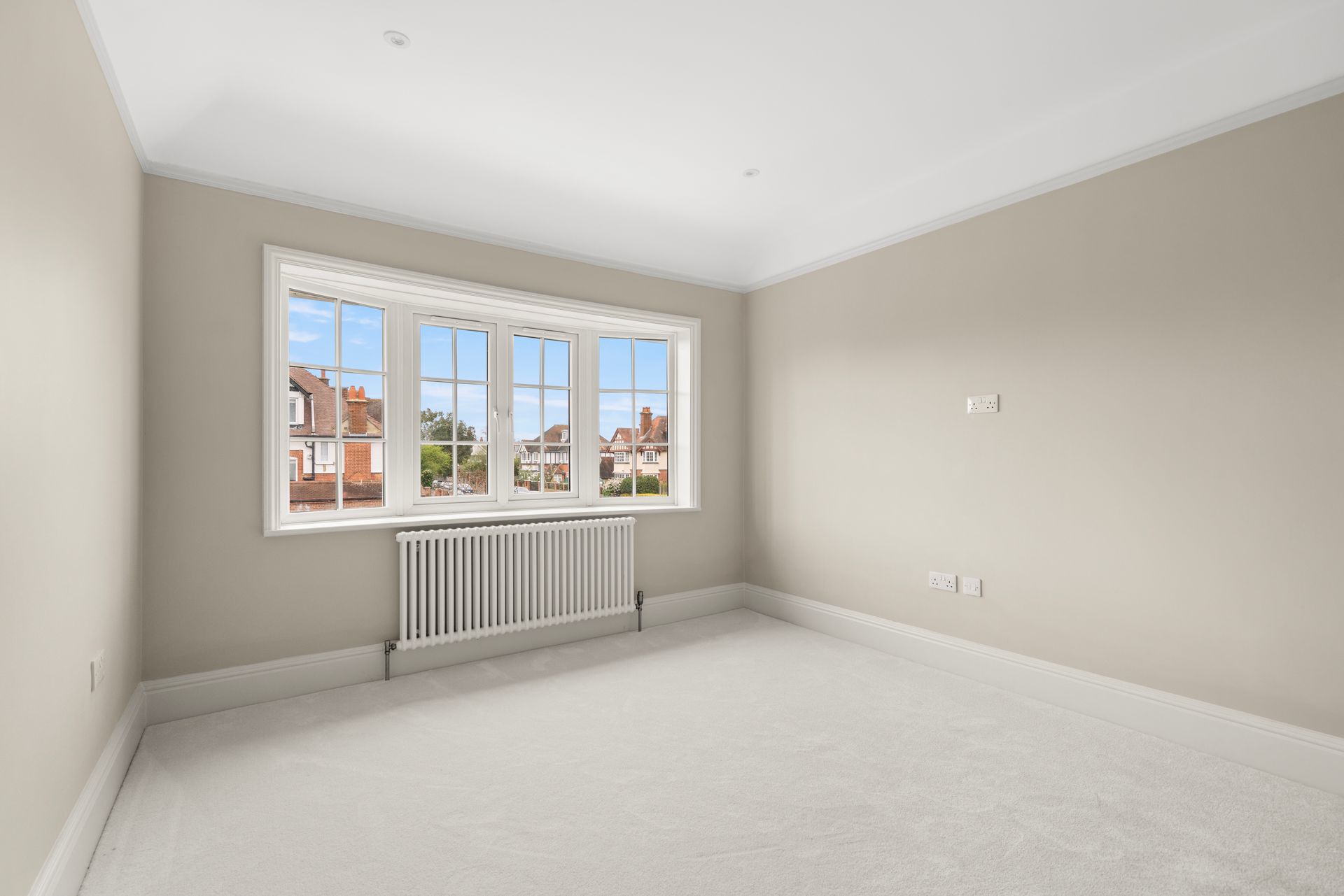 An empty bedroom with a large window and a radiator.