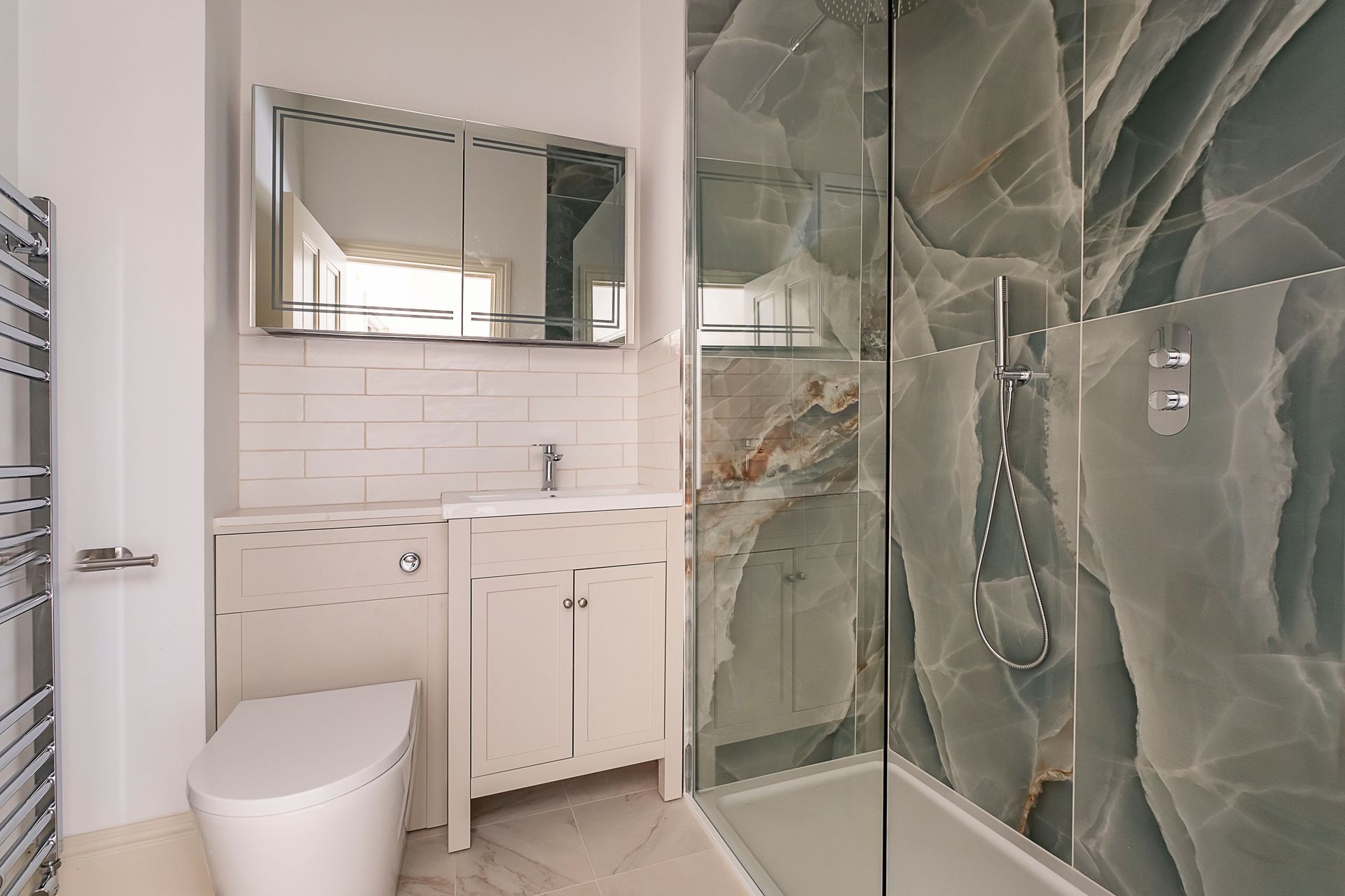 Bathroom with a vanity, toilet, shower, and patterned green wall tile.