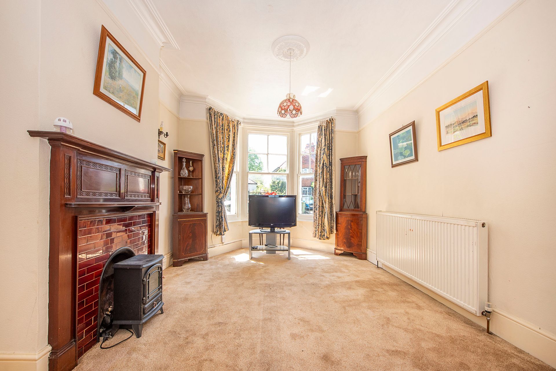 Living room with a fireplace, bay window, and two wooden display cabinets.