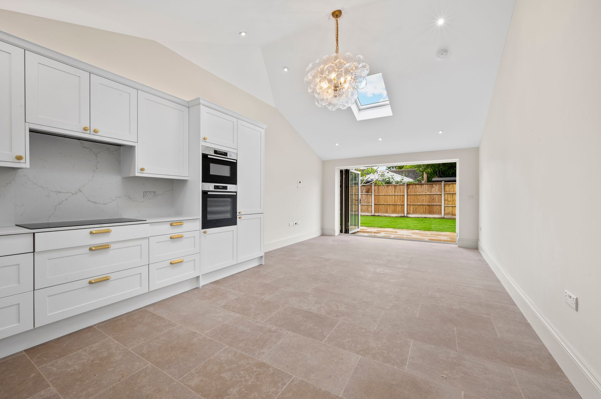 White kitchen with gold accents, opens to a backyard.