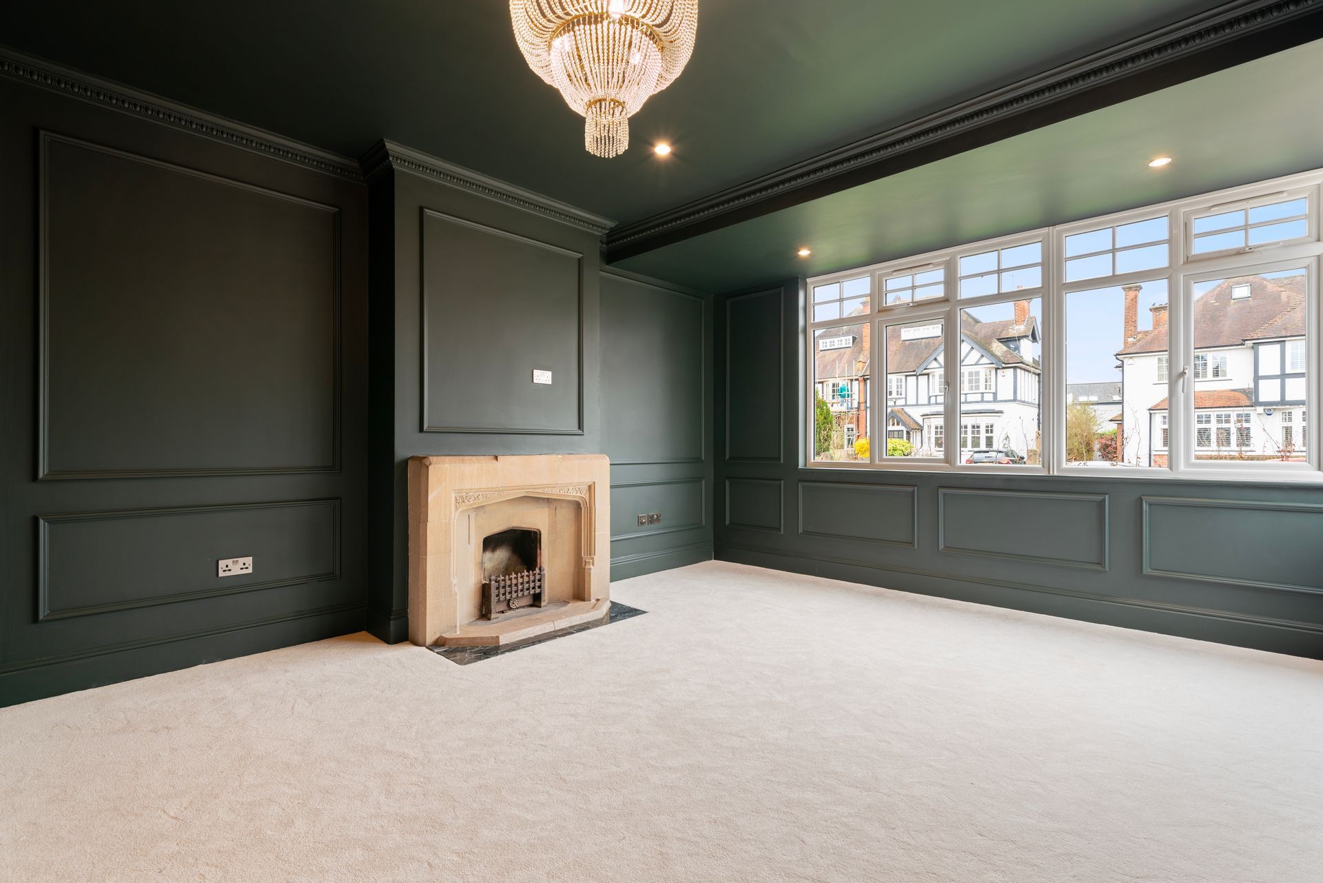 An empty living room with a fireplace and a chandelier.