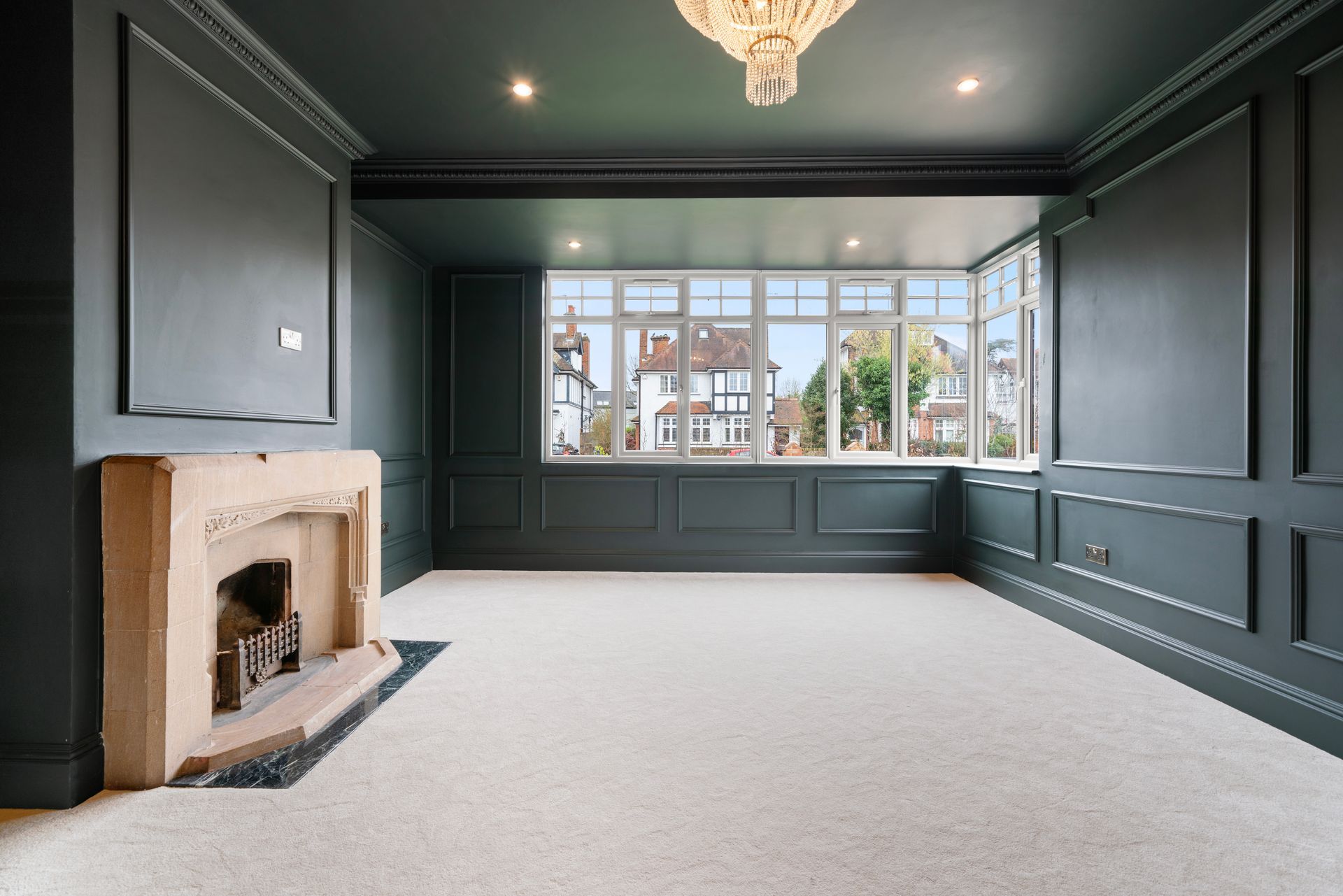 An empty living room with a fireplace and a chandelier.