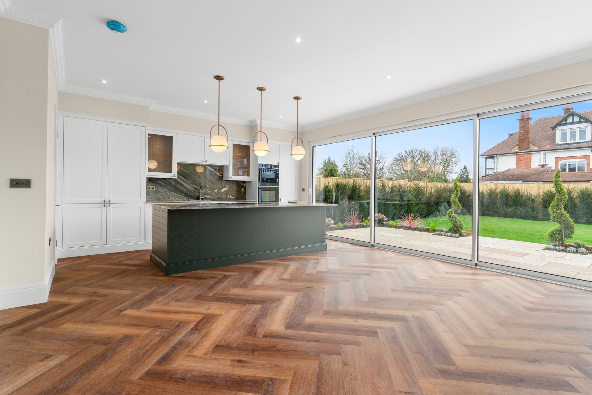 An empty kitchen with a large island and sliding glass doors.
