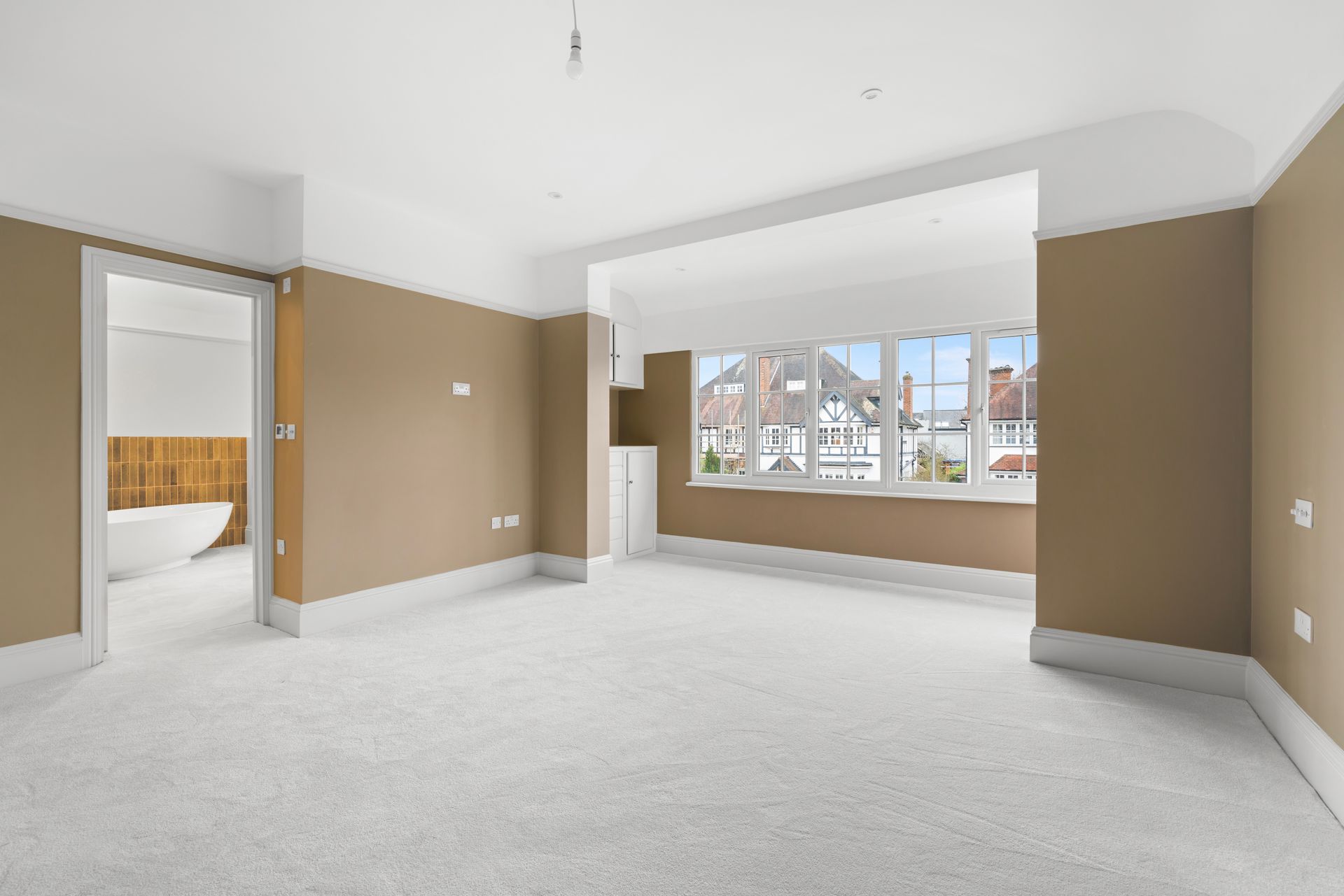 An empty living room with brown walls and white carpet.