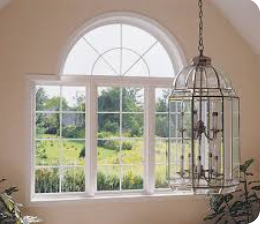 A large, arched window with a view of a green field, and a decorative hanging light.