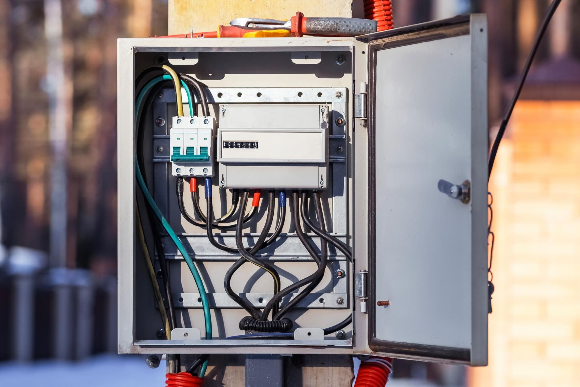 Open electrical box on a pole; wires and circuit breakers visible.