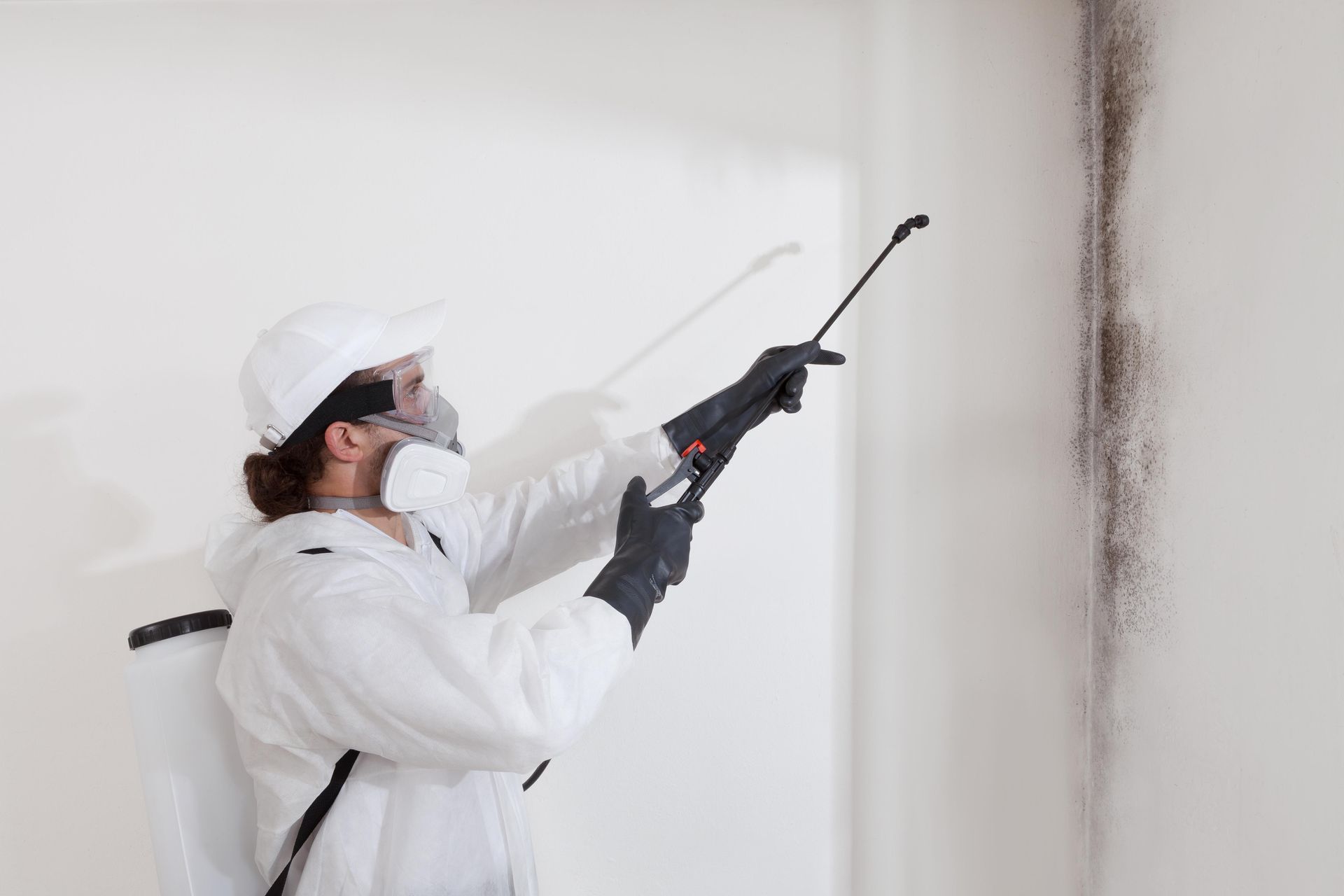 Person in protective suit spraying wall with mold.