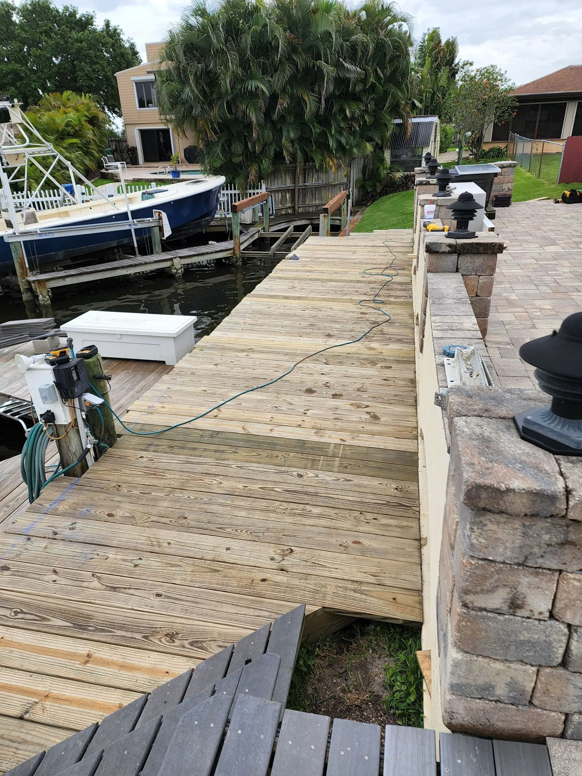 Dock leading to a boat, with a brick wall and steps. The dock appears to be made of light-colored stones.