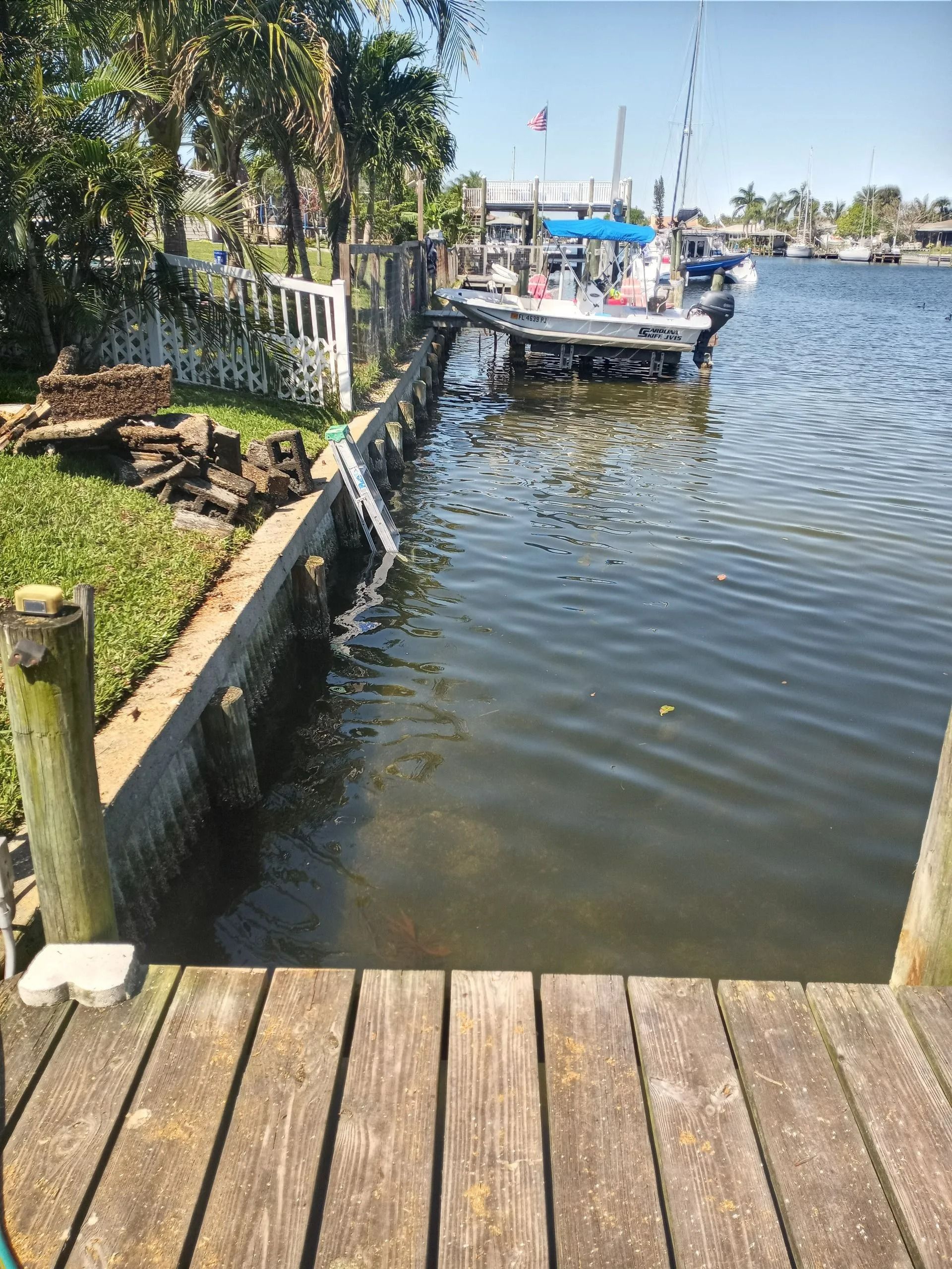 View of a dock and seawall with a boat docked in the water on a sunny day.