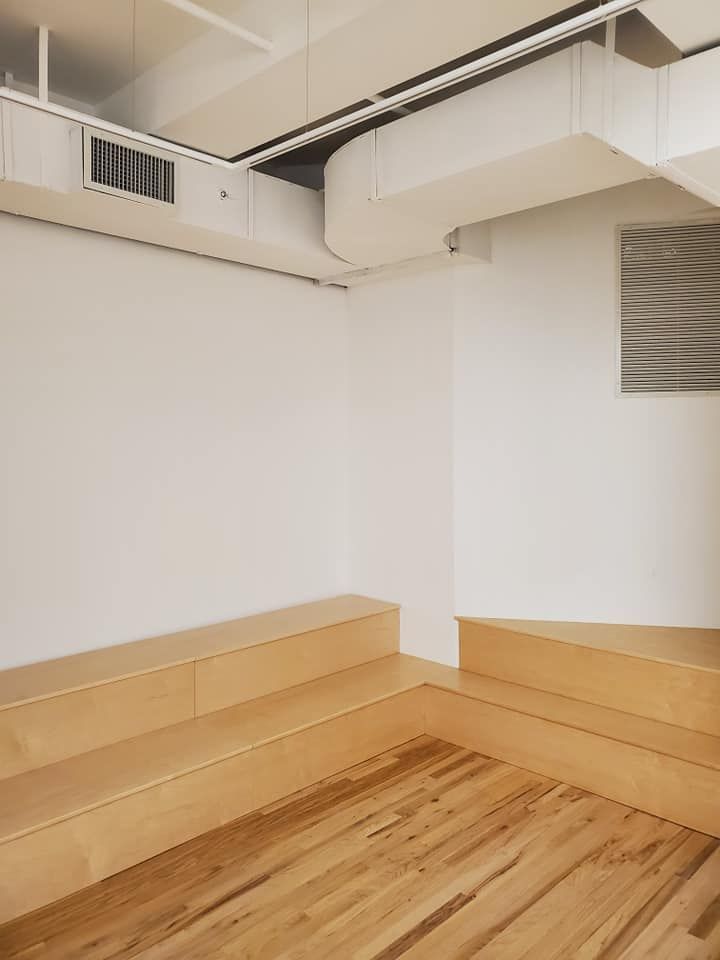 Basement corner with light wood flooring and steps, white walls, and a small window.