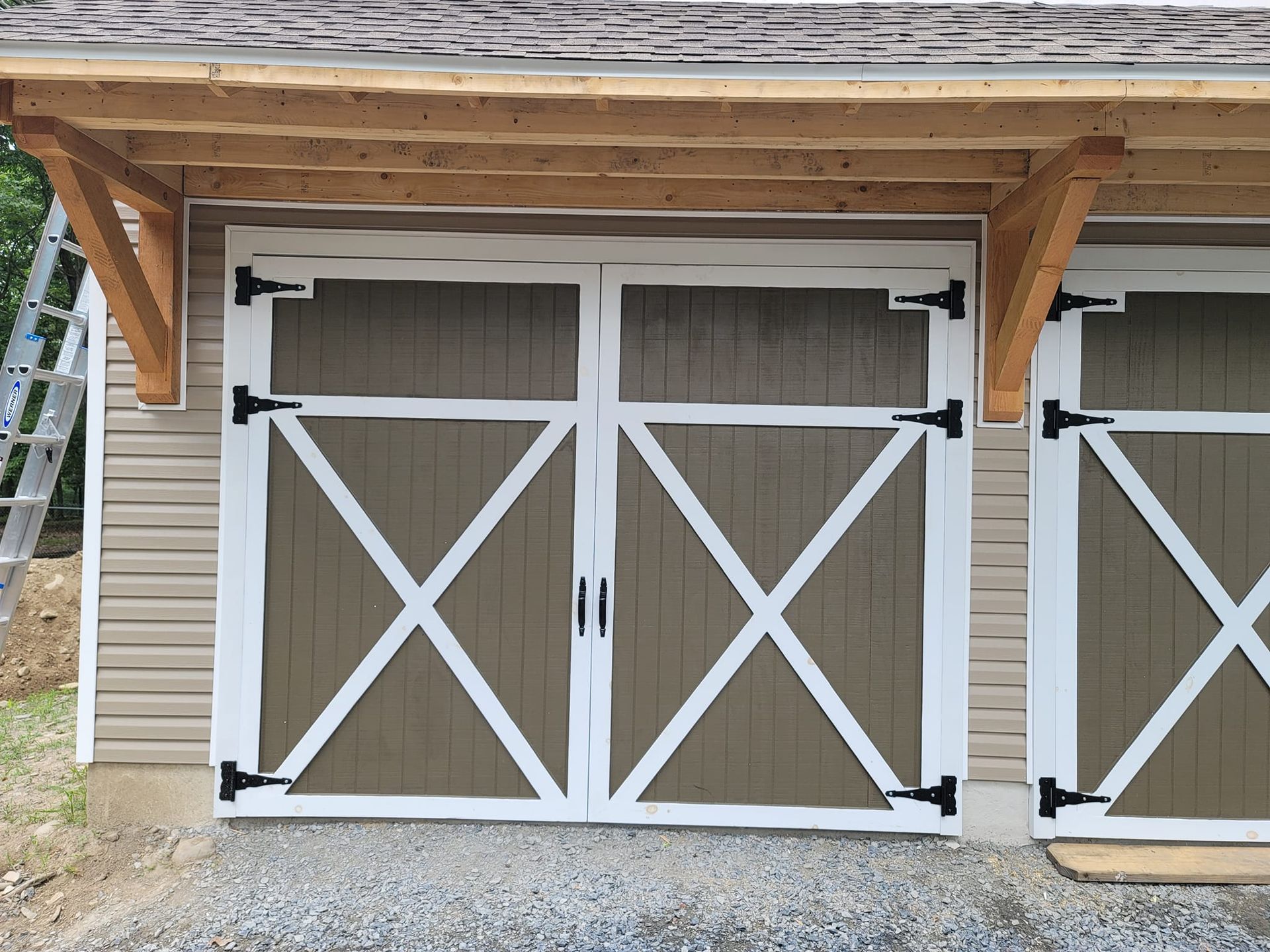 Tan barn doors with white crosses and black hinges; under a wooden canopy.