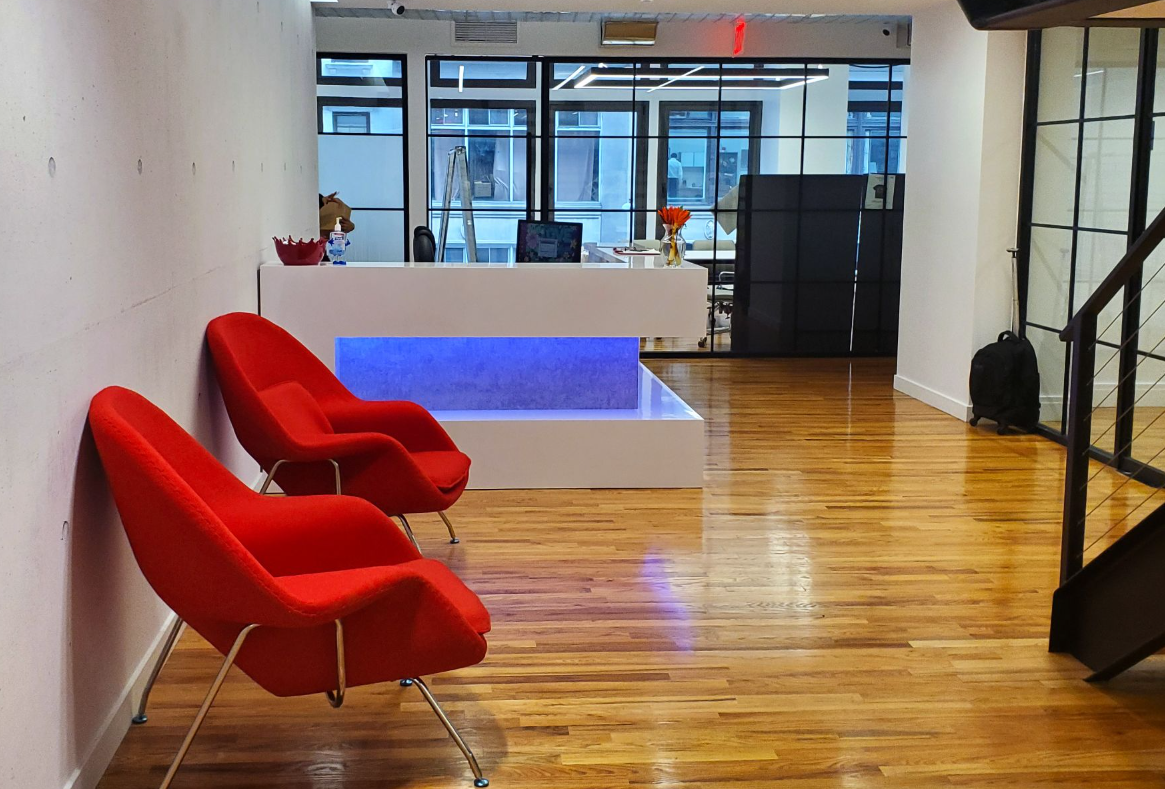 Two red chairs facing reception desk with blue light in office.