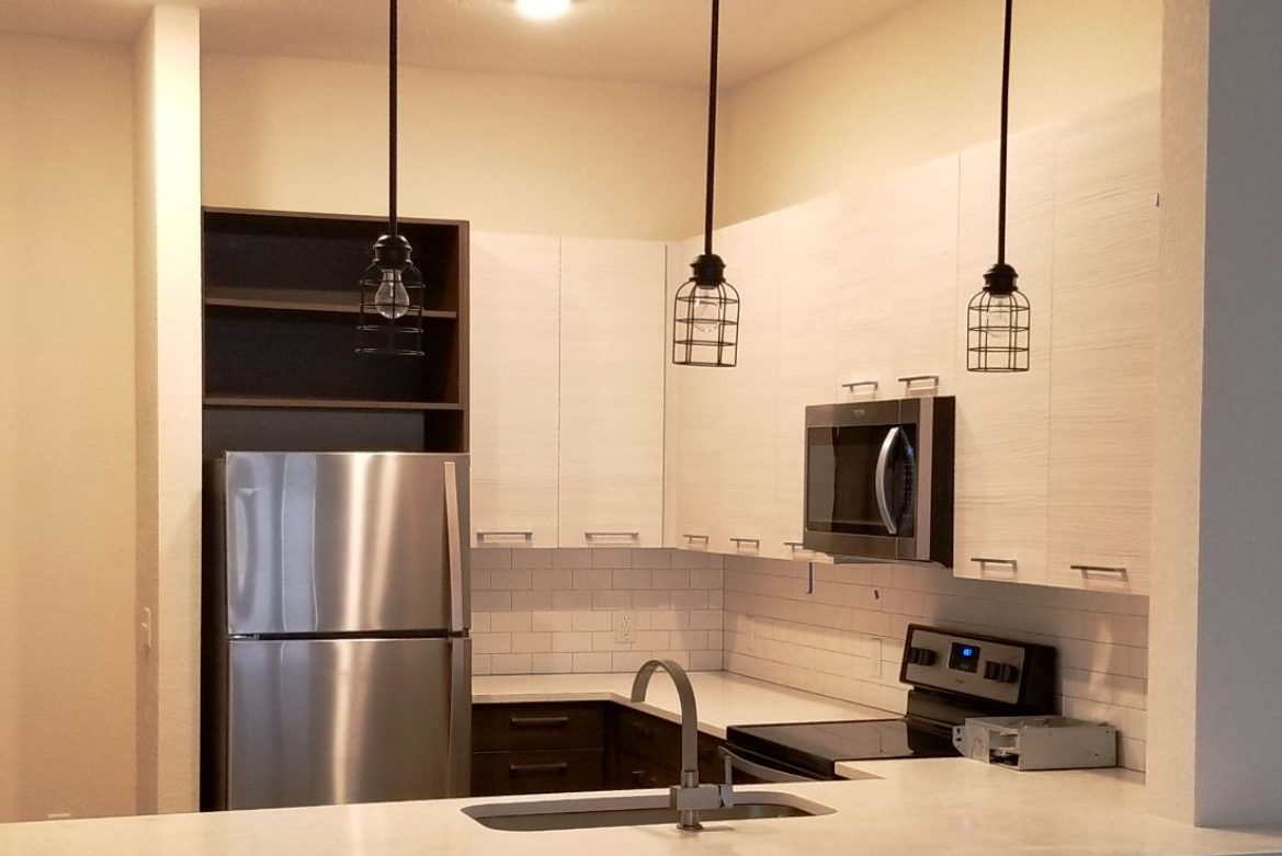 Kitchen with stainless steel appliances, white cabinets, and pendant lights.