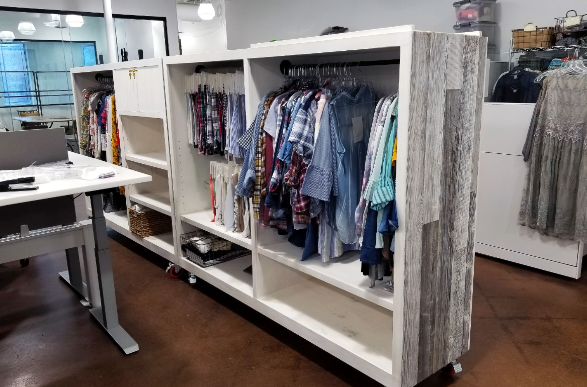 Clothing racks in a boutique with various shirts and a neutral color scheme.