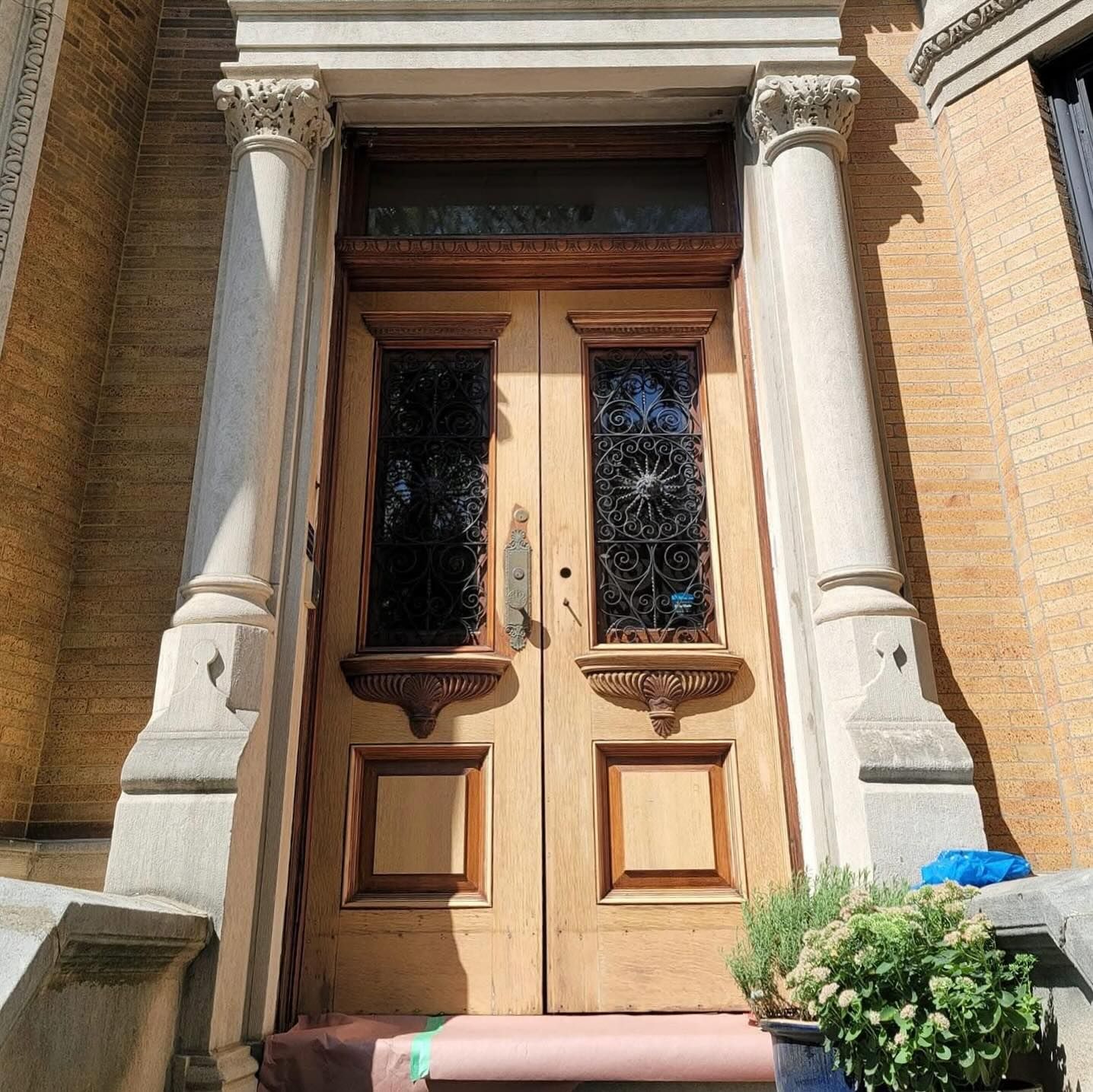 Double wooden entry doors with glass panels, framed by stone columns.