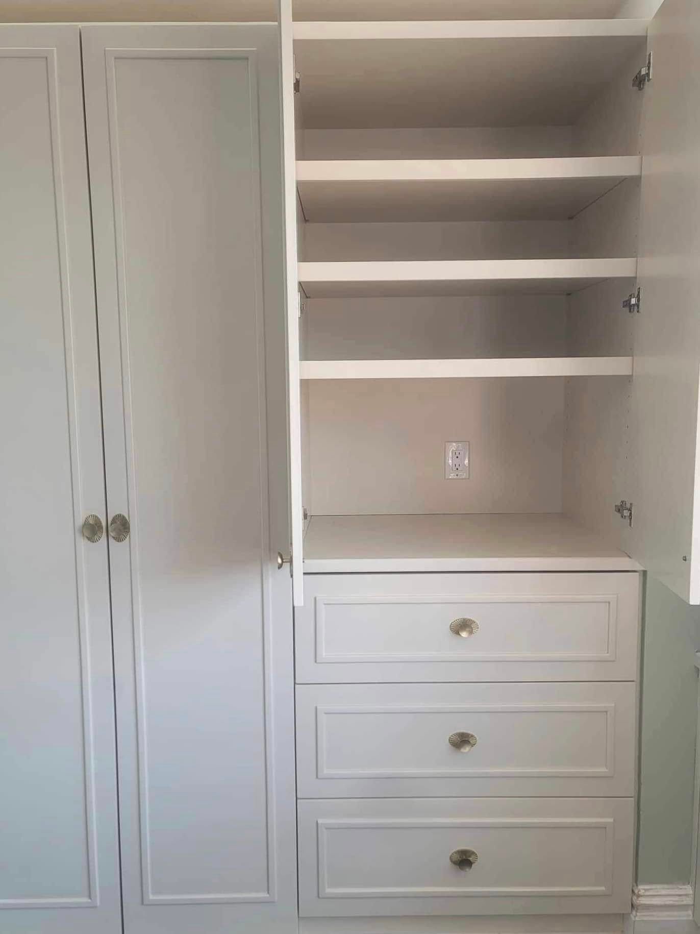 Light gray built-in closet with open door, revealing shelves and drawers; silver hardware.
