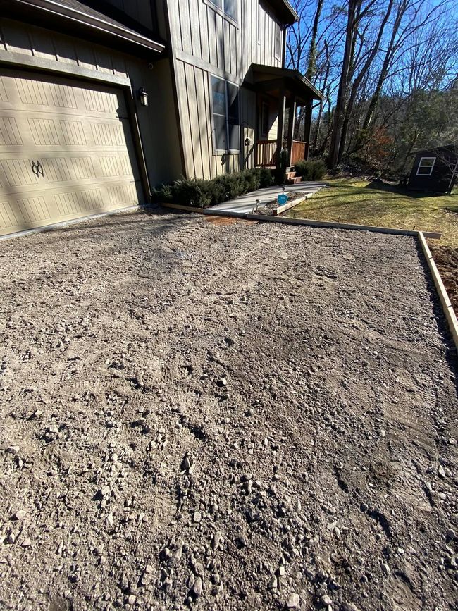 A gravel driveway is being built in front of a house.