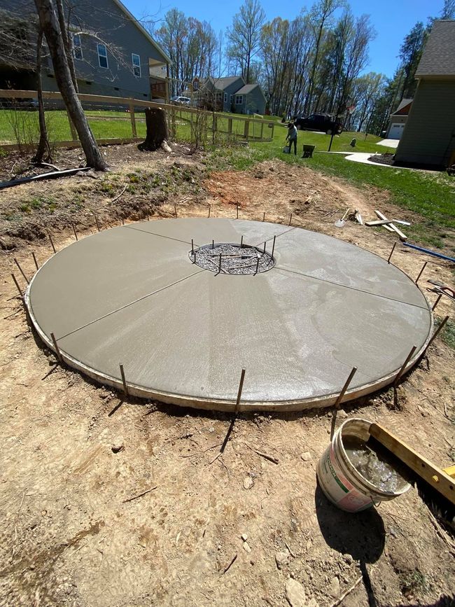 A large concrete circle is being built in a backyard.