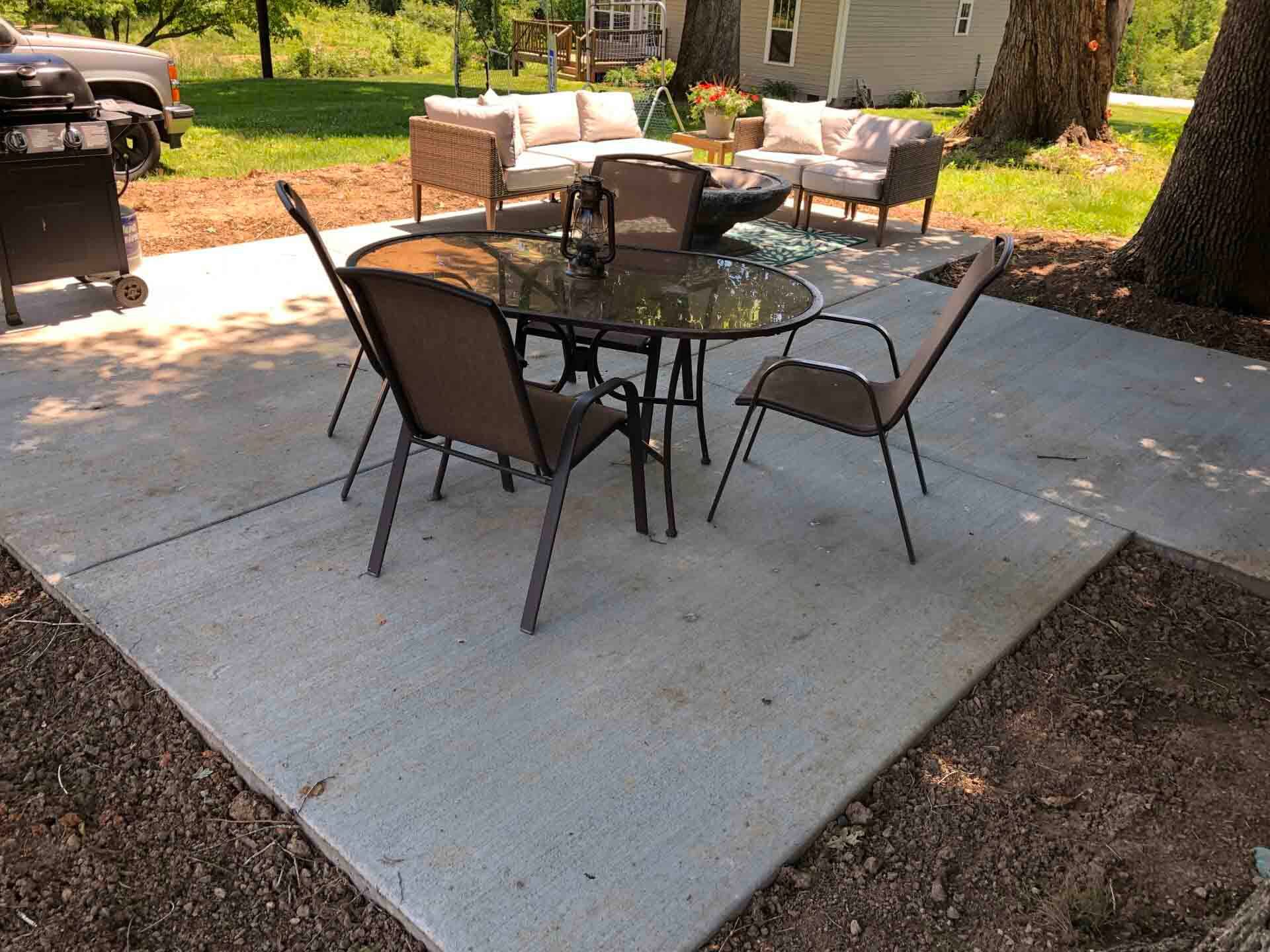 A patio with a table and chairs and a grill.