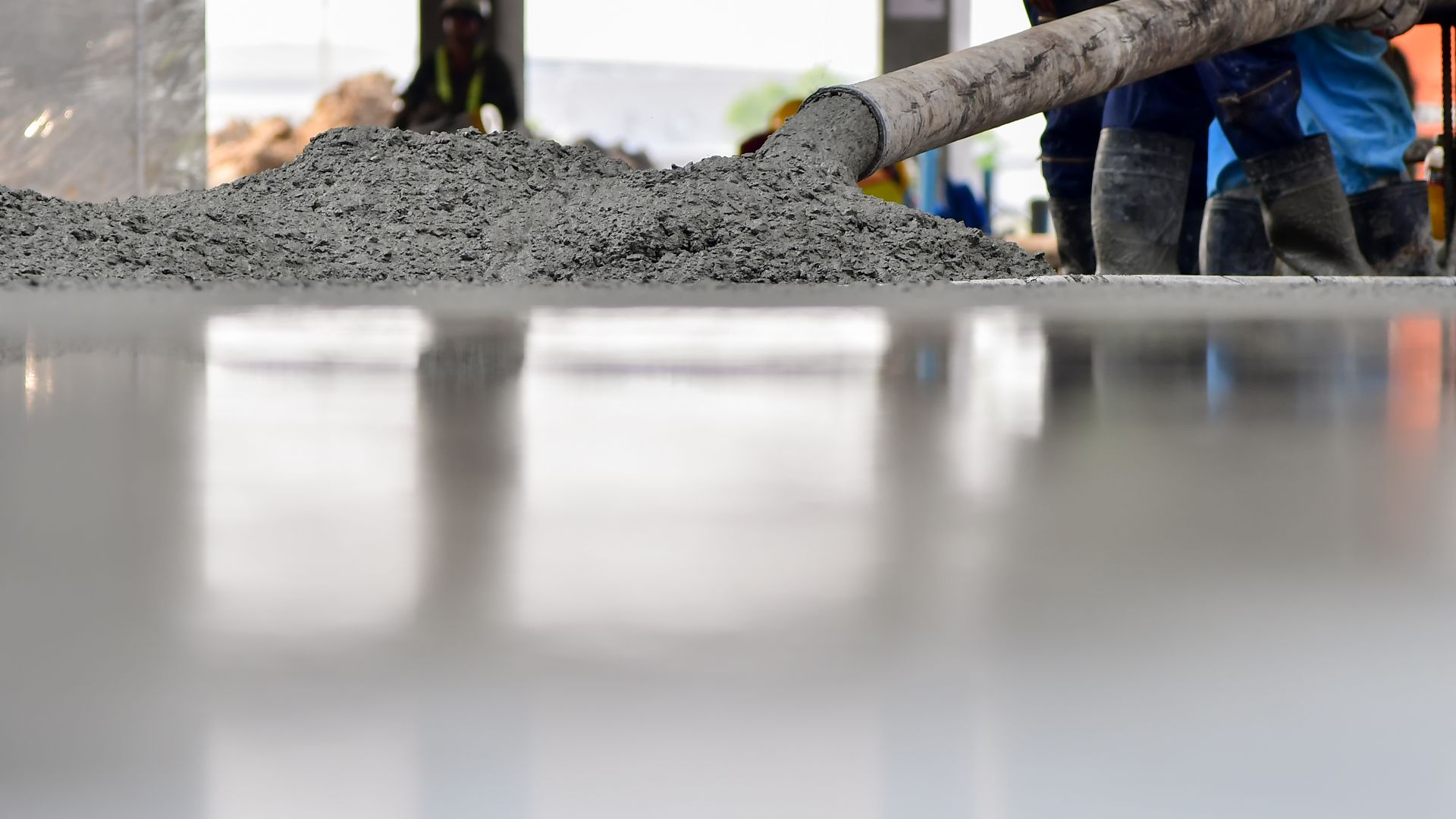 A person is pouring concrete into a concrete floor.