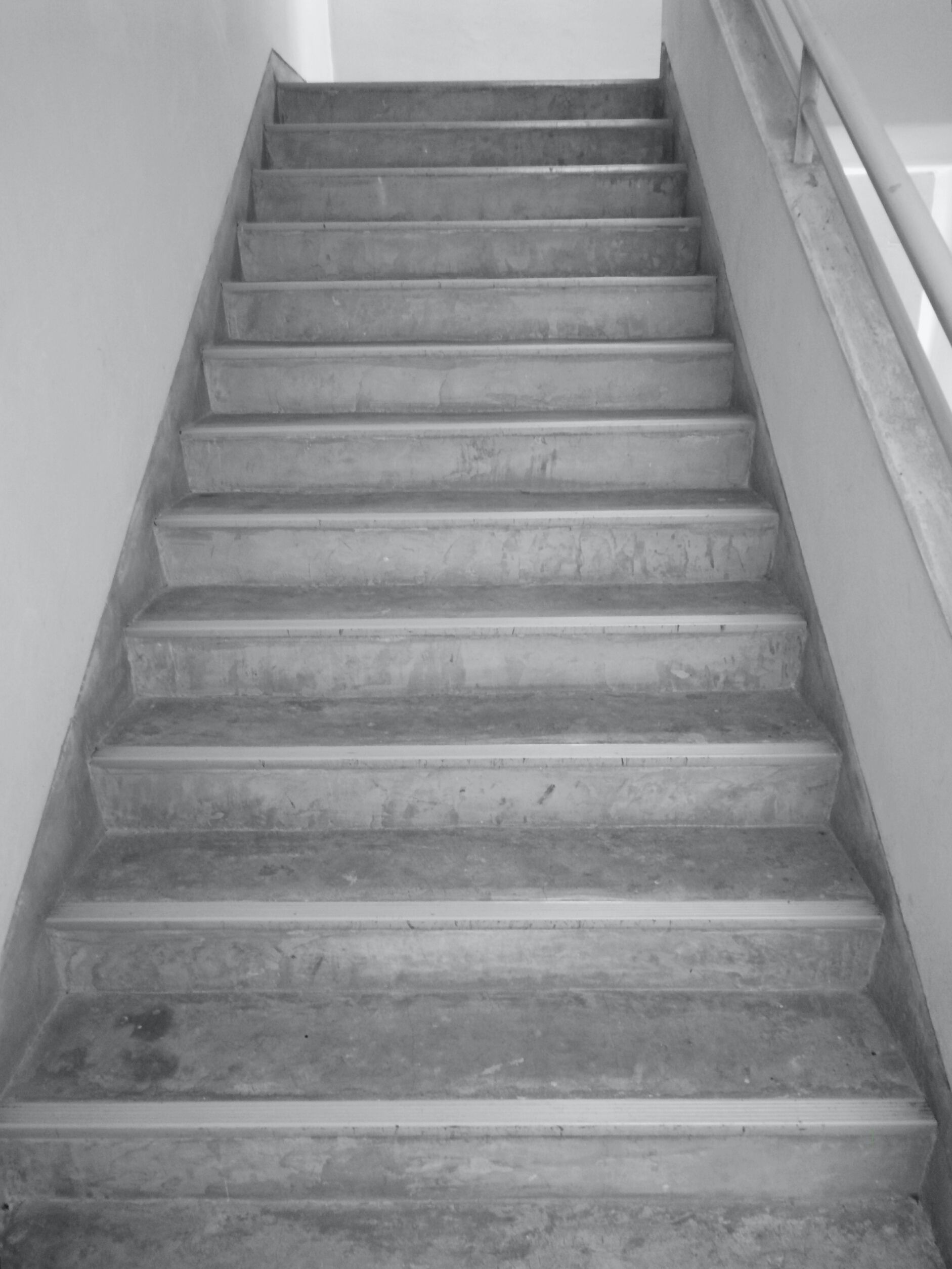 A black and white photo of a set of stairs with a railing.