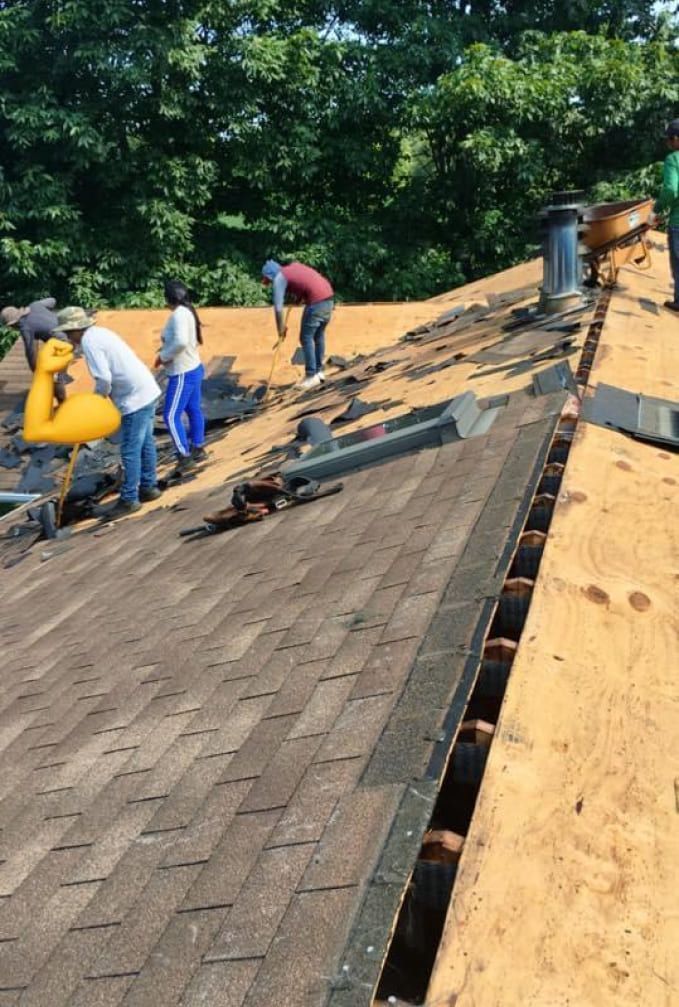 A group of people are working on a roof with their tools.