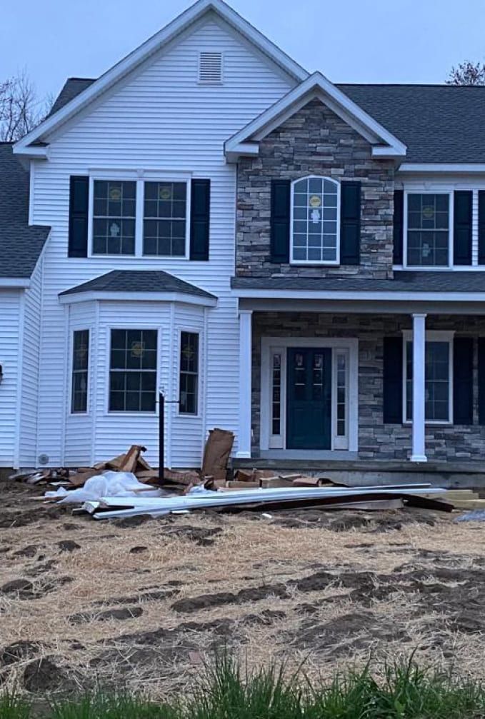 A large white house with black shutters is being built.