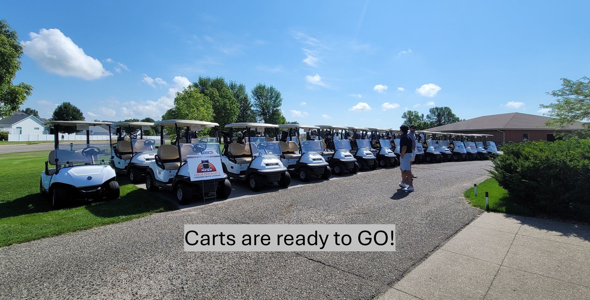 Row of golf carts parked on gravel, ready for use on a sunny day.