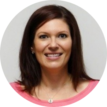 Woman with brown hair smiling, wearing a pink shirt, and a necklace.