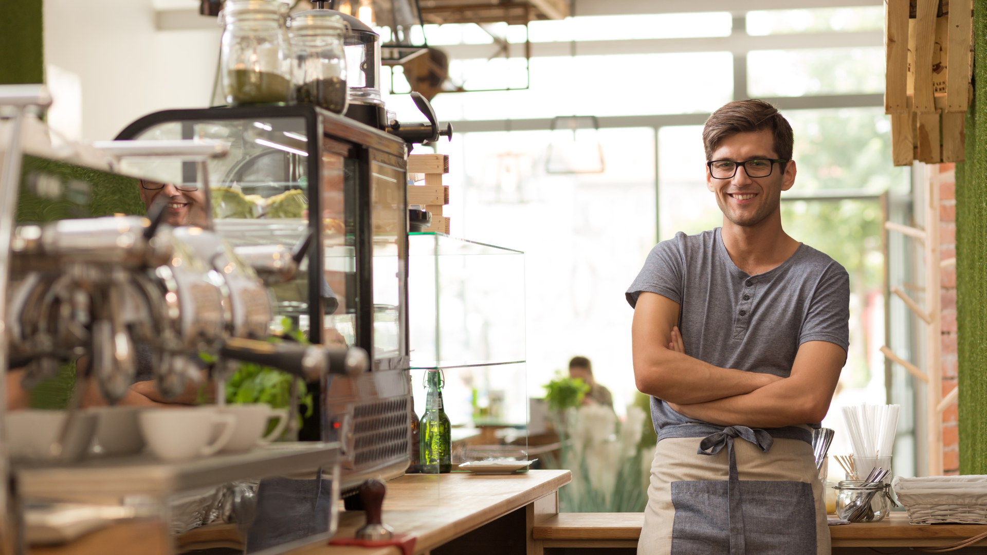 Un homme est debout dans un restaurant avec les bras croisés.