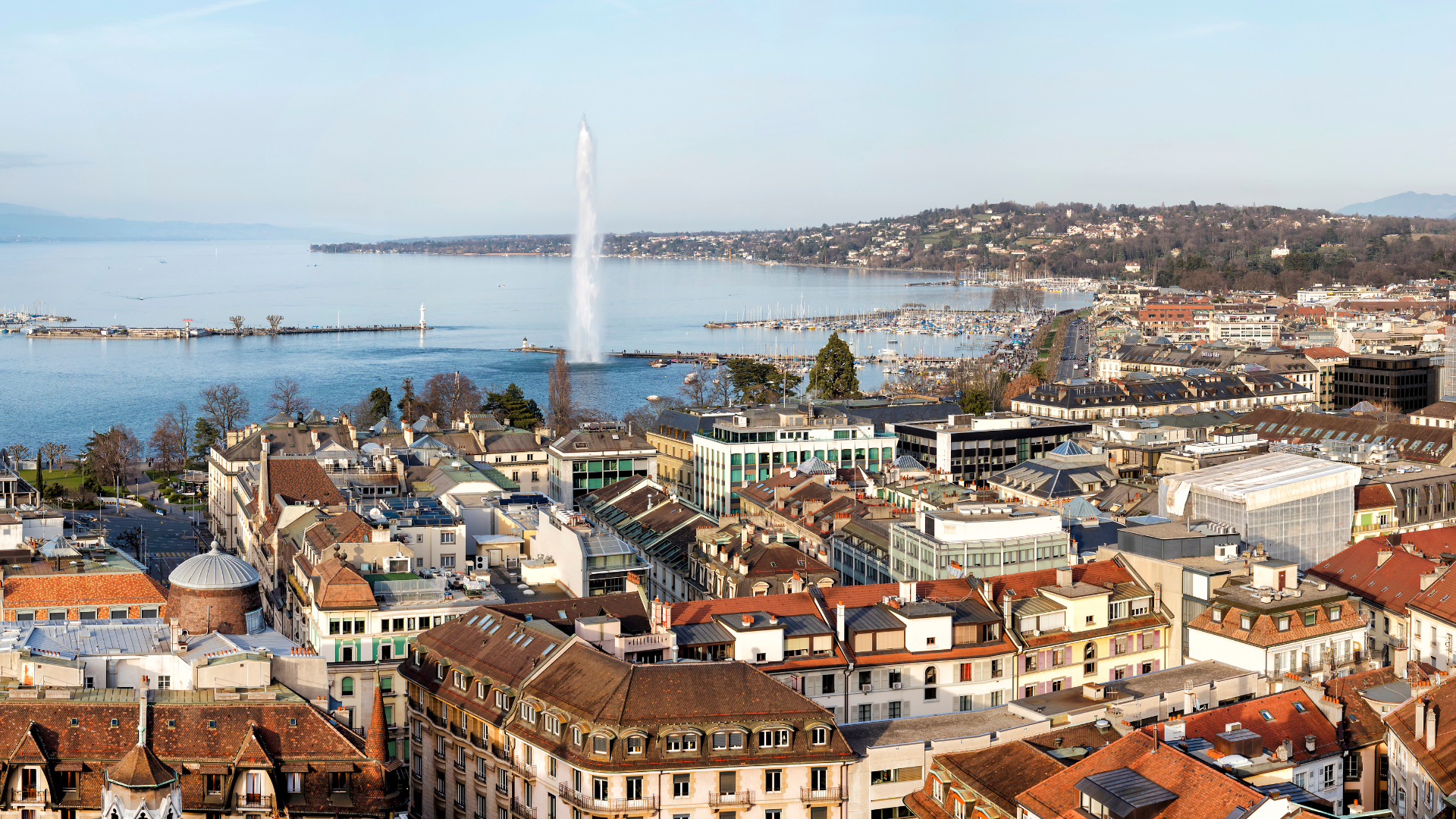 Geneva, Switzerland cityscape with lake, buildings, and water fountain.