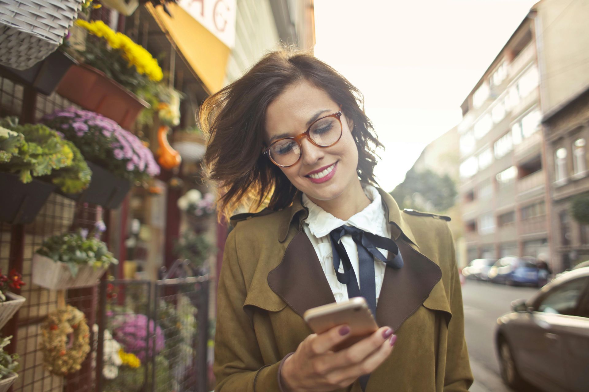 Une femme se tient sur un trottoir et regarde son téléphone portable.