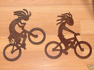 Two metal Kokopelli figures riding bicycles.