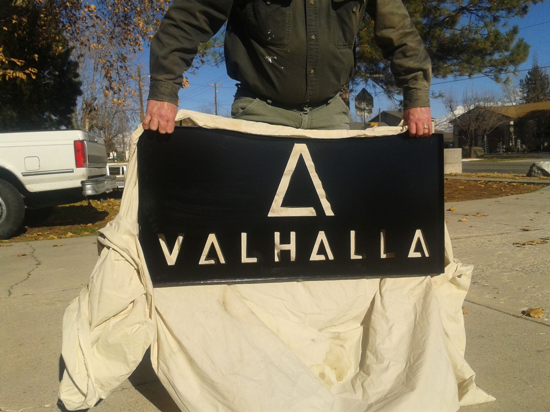 Man holding a black sign with a white triangle symbol and the word 