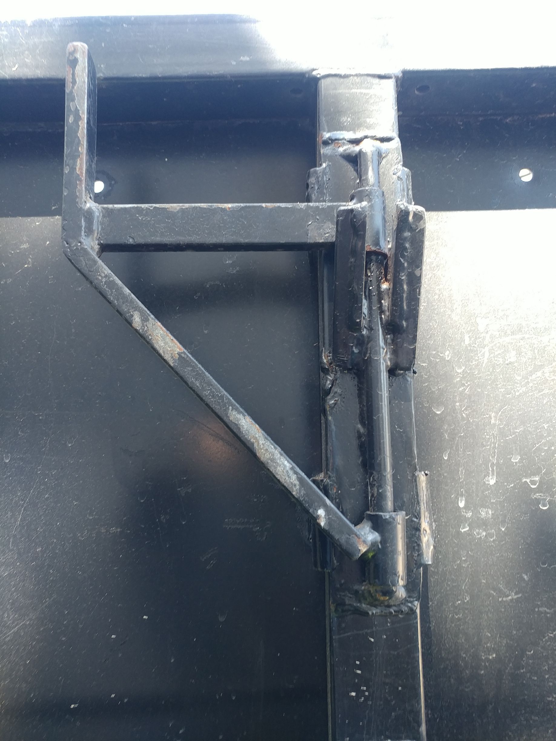Black metal latch on a black container. The latch has a lever arm.